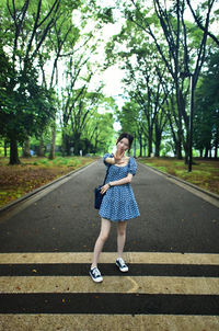 Full length of woman standing on road against trees