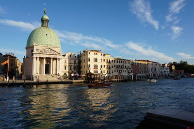 Buildings by river against sky