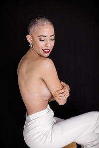 Side view of shirtless man standing against black background