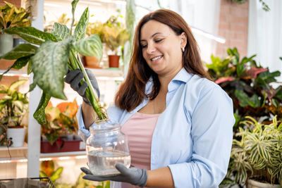 Portrait of young woman holding potted plant