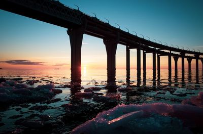 Bridge over sea against clear sky during sunset