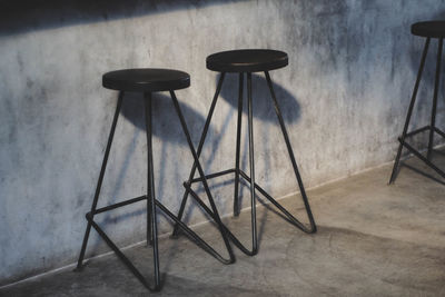 Close-up of empty chairs on table against wall