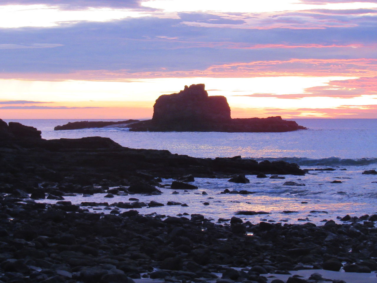 ROCKS ON SEA SHORE AGAINST SUNSET SKY