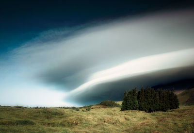 Scenic view of land against lenticular clouds in sky