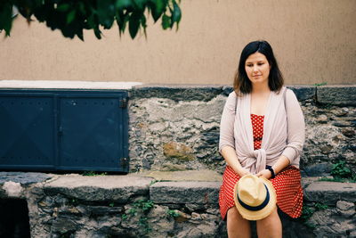 Young woman smiling while standing against wall