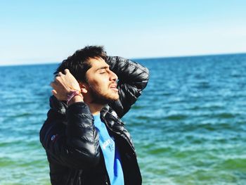 Young man standing in sea against clear sky