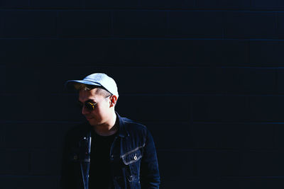 Young man standing by wall