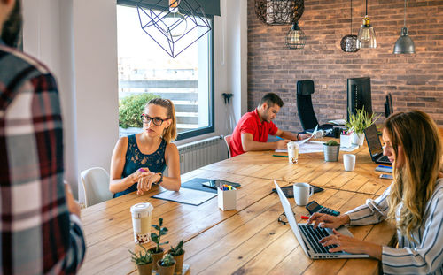 Angry female manager discussing with man for coming late to office