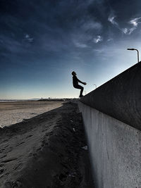 Low angle view of man jumping on land against sky