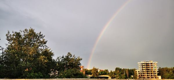 Low angle view of rainbow over building against sky