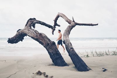 Young woman on sand at beach against sky