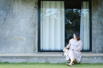 Woman sitting with cat against window