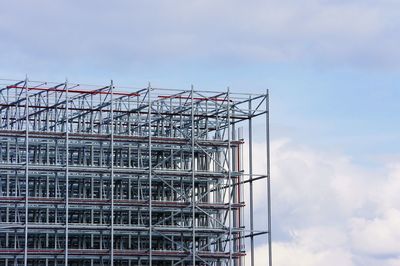 Low angle view of cranes at construction site against sky