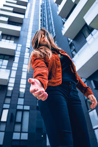 Low angle view of woman standing against building in city