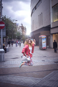 Woman walking on sidewalk by street against buildings in city