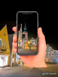 Close-up of hand holding mobile phone at night