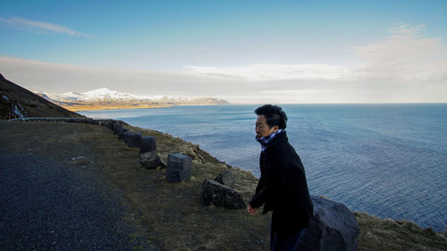 Senior woman standing against sea