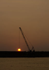 Cranes at construction site against sky during sunset