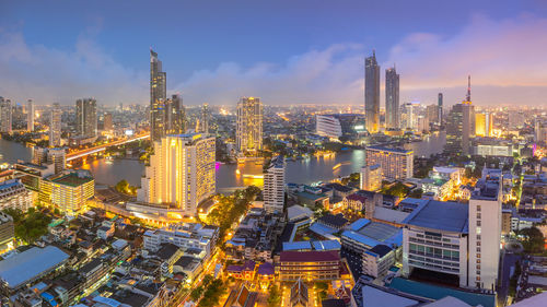 Illuminated buildings in city against sky