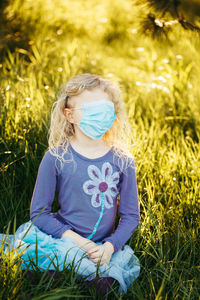 Girl wearing mask sitting on field
