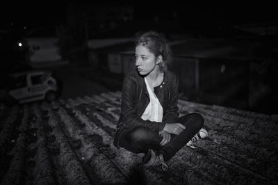 Thoughtful woman sitting on roof at night