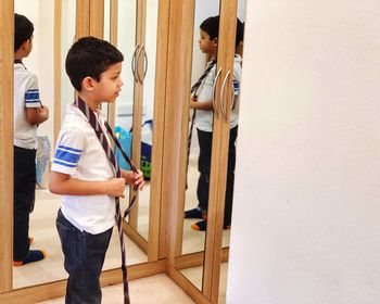 Reflection of boy wearing tie on mirror at home