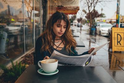 Woman holding coffee cup on table at cafe