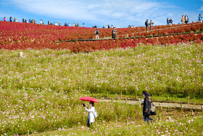 People on field by plants against sky