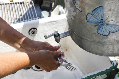 High angle view of hands washing spoon and fork in sink