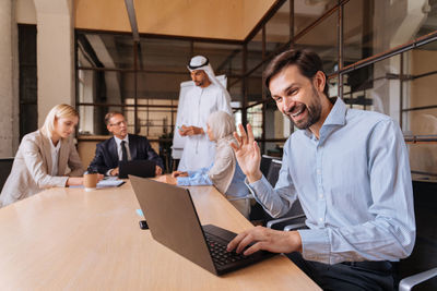 Portrait of young man using laptop while sitting in office