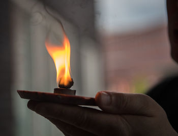 Close-up of hand holding burning candle