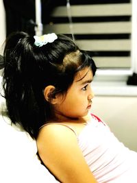 Side view of thoughtful girl sitting on bed at home