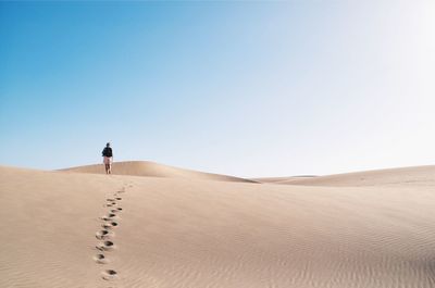 Person walking at desert against sky