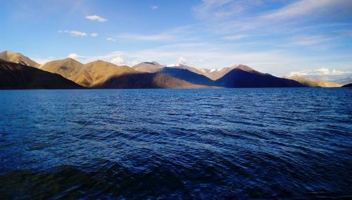 Scenic view of sea and mountains against blue sky