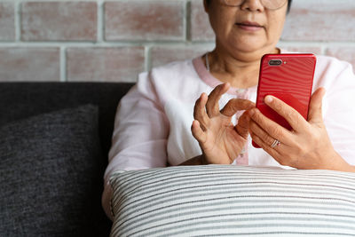 Senior woman using mobile phone while sitting on sofa at home