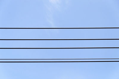 Low angle view of power lines against clear blue sky
