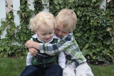 Portrait of two young brothers hugging in a fenced garden area