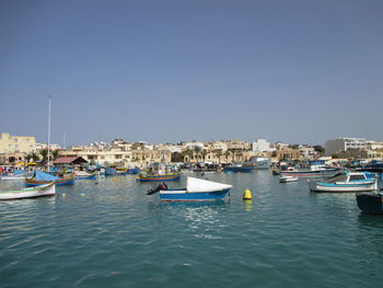 Boats moored in harbor against clear sky