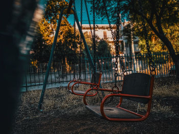 Empty park bench by trees in city