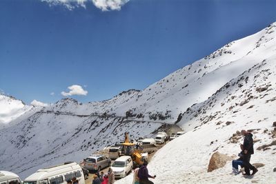 Panoramic view of people on snowcapped mountain against sky