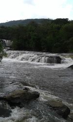 Scenic view of waterfall in forest against sky