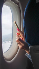 Midsection of man photographing through airplane window