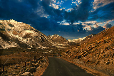 Road by mountains against sky