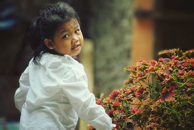 Side view of young woman standing against plants