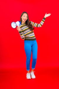 Portrait of smiling young woman standing against red background