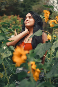 Thoughtful beautiful woman standing amidst plants