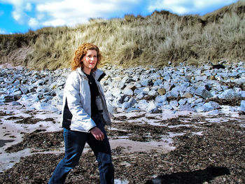 Smiling young woman walking on shore