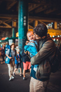 Side view of man kissing daughter while standing outdoors