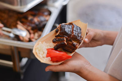 Cropped image of man holding meat in plate while standing at market stall