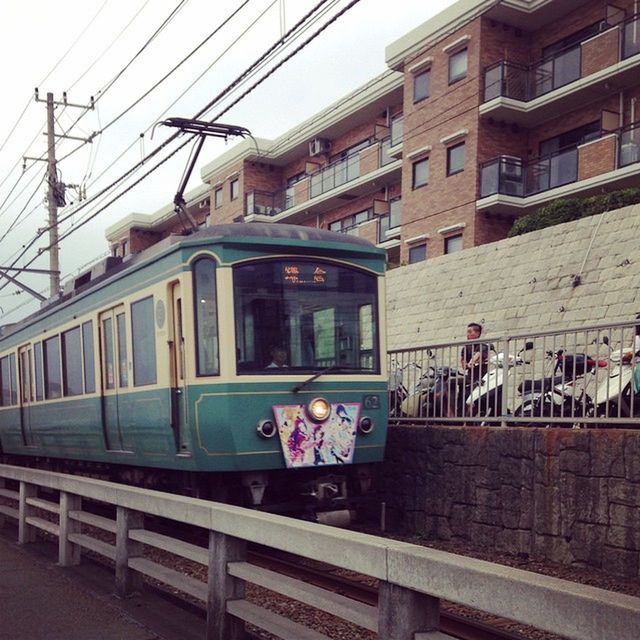 building exterior, architecture, built structure, transportation, railroad track, power line, rail transportation, public transportation, cable, mode of transport, railroad station, railroad station platform, electricity pylon, train - vehicle, city, sky, power supply, land vehicle, street, electricity